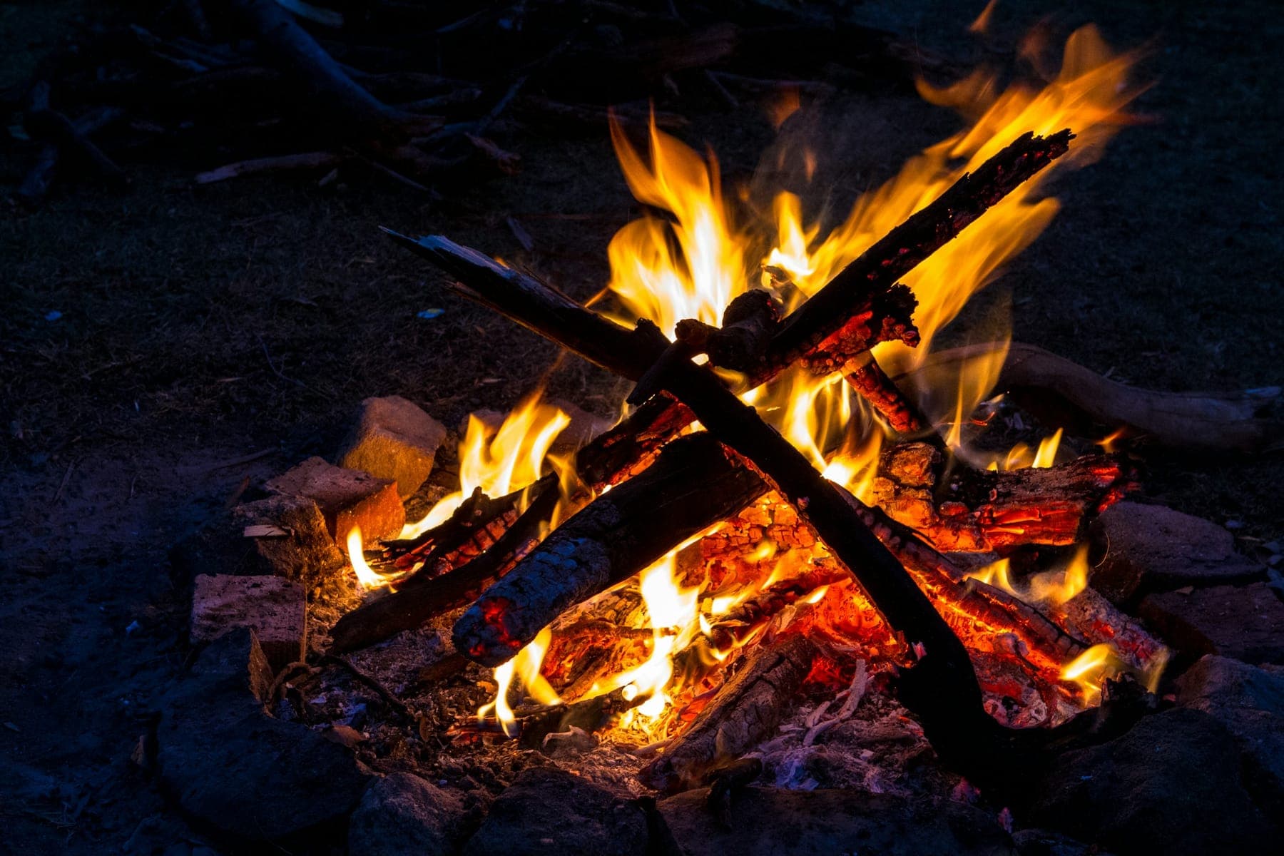 Ognisko nocą — płomienie nad rozżarzonymi polanami